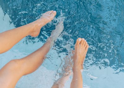 two people with their legs into the swimming pool